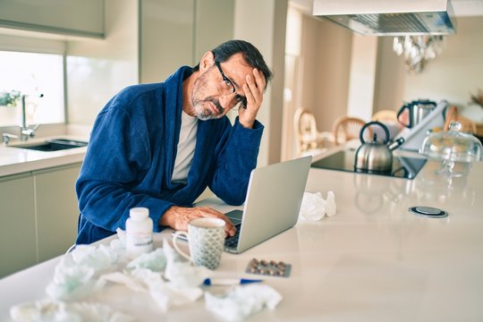 Middle age man feeling sick with cold and fever at home, ill with flu disease working from home