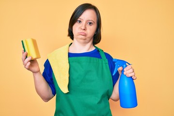Brunette woman with down syndrome wearing apron holding scourer depressed and worry for distress, crying angry and afraid. sad expression.
