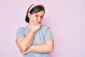 Brunette woman with down syndrome wearing casual clothes thinking looking tired and bored with depression problems with crossed arms.
