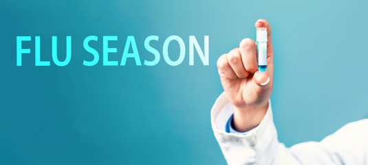 Flu Season Coronavirus theme with a doctor holding a laboratory vial on a blue background