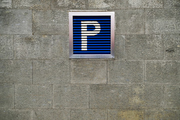 Big blue parking sign on a stone wall.