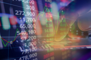 Fototapeta premium Businessman finger touching screen on smartphone with stock market graph at night.