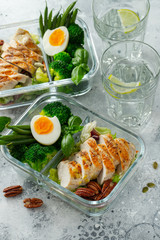 Healthy meal prep containers with green beans, chicken breast and broccoli. A set of food for keto diet in lunchbox on a light concrete background. Top view