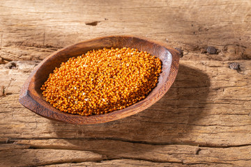 red millet grains in bowl on wood