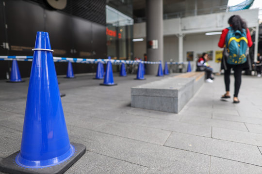 Blue witches hat cone traffic warning sign  barrier applying on busy street downtown on pedestrian footpath construction site in Sydney city CBD,  Australia 