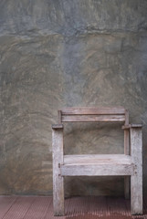 Obraz na płótnie Canvas Empty, wooden old chair with old dirty cement color grey wall vintage background. Empty free space.