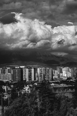 Beautiful and scenic sunlight and cloudy sky over Santiago skyline, Santa Lucía hill and the snowed The Andes Mountains, Chile (in black and white)