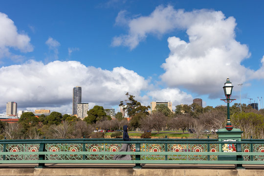 Person walking by the Albert bridge, named after Queen Victoria&rsquo;s husband, Prince Albert. Park and high buildings from the city at the background. Adelaide, Australia