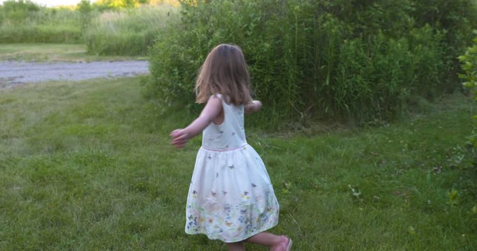 Cute little girl spinning in circles holding a sparkler.
