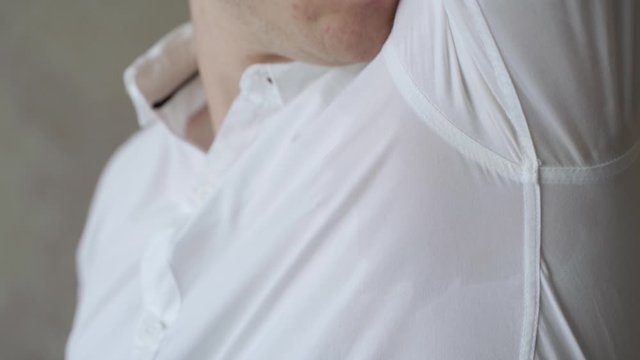 Adult Male Wearing White Shirt Lifting Up Left Arm To Reveal Sweat Patch. Slow Motion
