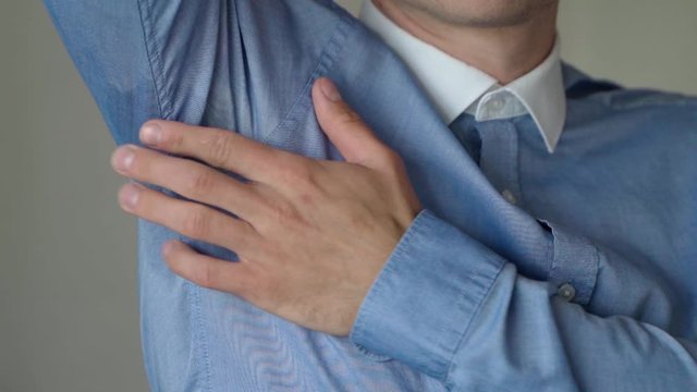 Male Wearing Blue Shirt Lifting Up Left Arm To Touch Sweat Patch With Hand. Slow Motion, Locked Off 