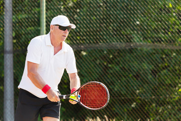 Close-up of an elderly tennis player playing tennis on an outdoor court