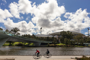 Two people cycling in front of the Adelaide Oval, sports stadium used for cricket, Australian...