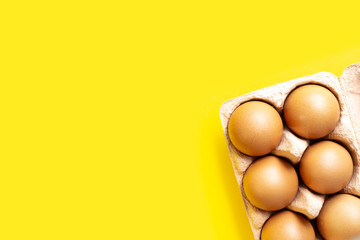 Homemade eggs in cardboard packaging in the corner on a yellow background. With place for text. Ecology and recycling concept. Layout or flat lay.