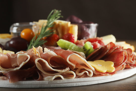 Brie, gouda, asiago, parmesan, cup, salami, jamon, apricots with gorgonzola, plums with cream chease and fruit. Antipasto dish on wooden table. Selective focus