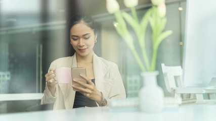 Portrait of female relaxing with smartphone while take a break with coffee