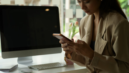 Cropped shot of female entrepreneur using smartphone while at office desk