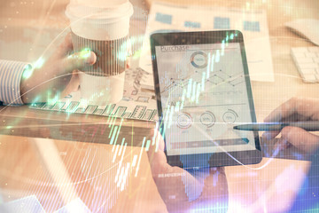 Double exposure of man's hands holding and using a phone and financial chart drawing. Market analysis concept.