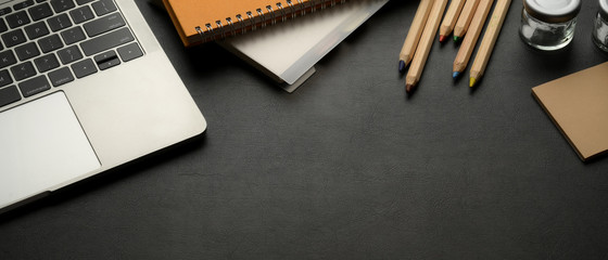 Workspace with laptop, stationery, supplies and copy space on black leather table