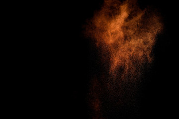 Fototapeta na wymiar Orange powder explosion on black background. Colored powder cloud. Colorful dust explode. Paint Holi.