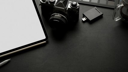 Workspace with mock up tablet, camera, accessories and copy space on black leather table