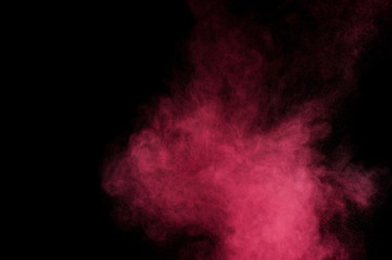 Red and pink powder explosion on black background. Colored powder cloud. Colorful dust explode. Paint Holi.