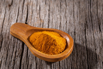 Turmeric powder in bowl on wooden background