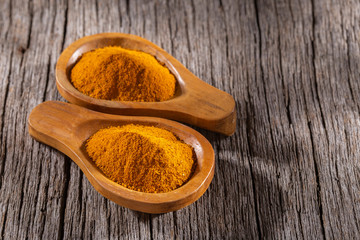 Turmeric powder in bowl on wooden background