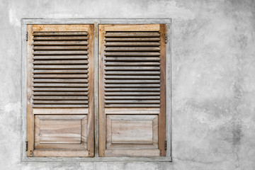 Window with closed wooden shutters. Gray concrete cement wall background.