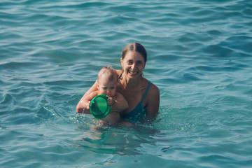 A young mother and daughter swim in the sea. swimming training.
