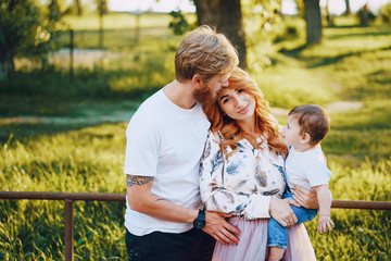 Beautiful red-haired woman with her husband and a wonderful son on a summer park