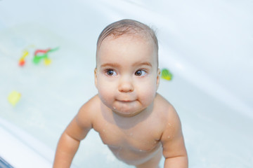 Little girl bathing in the bathroom. The child washes in a basin with toys