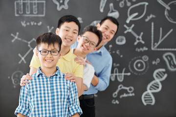 Group of Vietnamese school students and their chemistry teacher standing one behind another and...