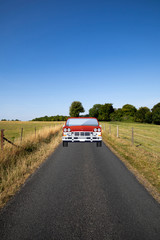 Car travelling down a single lane country road through countryside and farmland