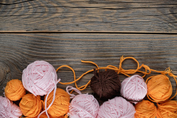 Female hobbies, knitting. Yarn in warm colors on wooden table. Pink, yellow, and braun. Frame made...