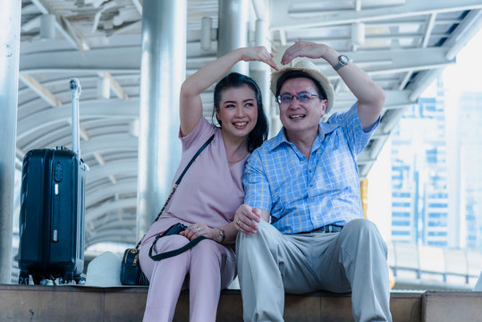 tourist woman and man wearing casual dress , hand holding baggage for travel sitting and talking about map on hand at the public sky walk bridge.