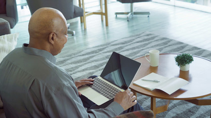 Business senior old elderly Black American man, African person working from home on table with computer notebook laptop and blank screen on webcam video call conference in quarantine in corona virus.