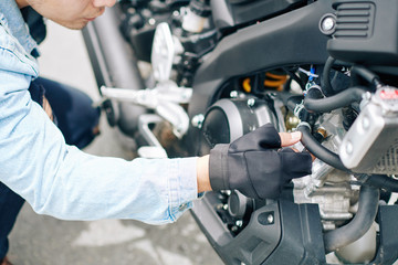 Close-up image of serious motorcyclist changing pipes in his broken bike and searching for breakage