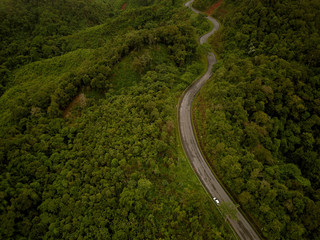 Logistic concept aerial view of countryside road - motorway passing through the serene lush greenery and foliage tropical rain forest mountain landscape