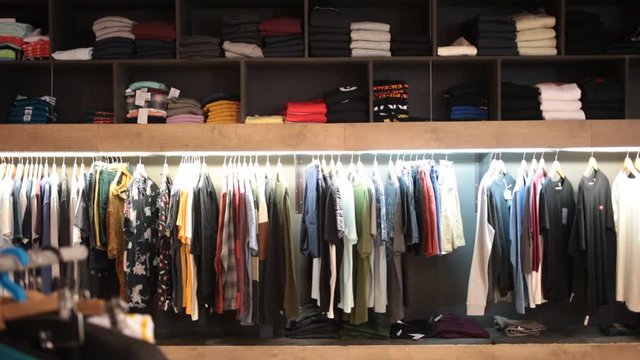 Men clothing shop, casual clothes on hangers and shelves in apparel store 