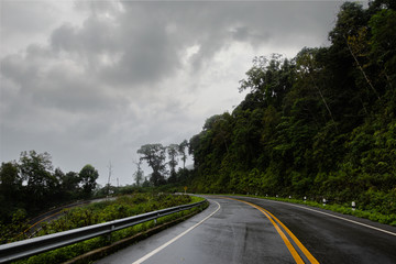 Logistic concept aerial view of countryside road - motorway passing through the serene lush greenery and foliage tropical rain forest mountain landscape