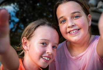 children make selfie in the park.  two girls taking pictures of themselves against the background of a pond