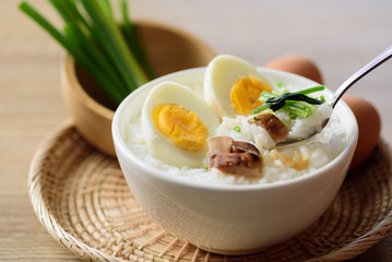 Asian food, Rice soup with boiled egg, grilled mushroom and spinach in a bowl on woven rattan sheet