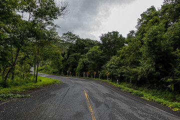 Logistic concept aerial view of countryside road - motorway passing through the serene lush greenery and foliage tropical rain forest mountain landscape