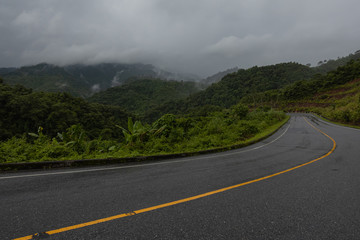 Logistic concept aerial view of countryside road - motorway passing through the serene lush greenery and foliage tropical rain forest mountain landscape