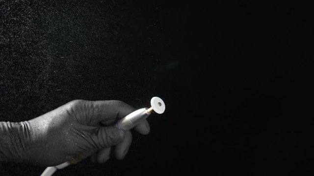 Close-up view of rotating bor machine in dentist hand shot on black background in dental office, Slow motion of Polishing Edge of Dental Crown. Full hd