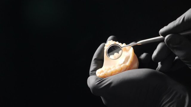 Close-up view of rotating bor machine in dentist hand shot on black background in dental office, Slow motion of Polishing Edge of Dental Crown. Full hd