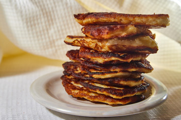 Pancakes on a white plate and white background. Delicious fried flour food. Unhealthy and harmful, but very tasty food.