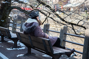 Young woman sitting on the bench in the park in winter.