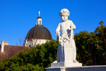 Fototapeta na wymiar Sculpture of a boy in the gardens of Belvedere palace . Symbolic statue of september month . Monument of a boy with fruits